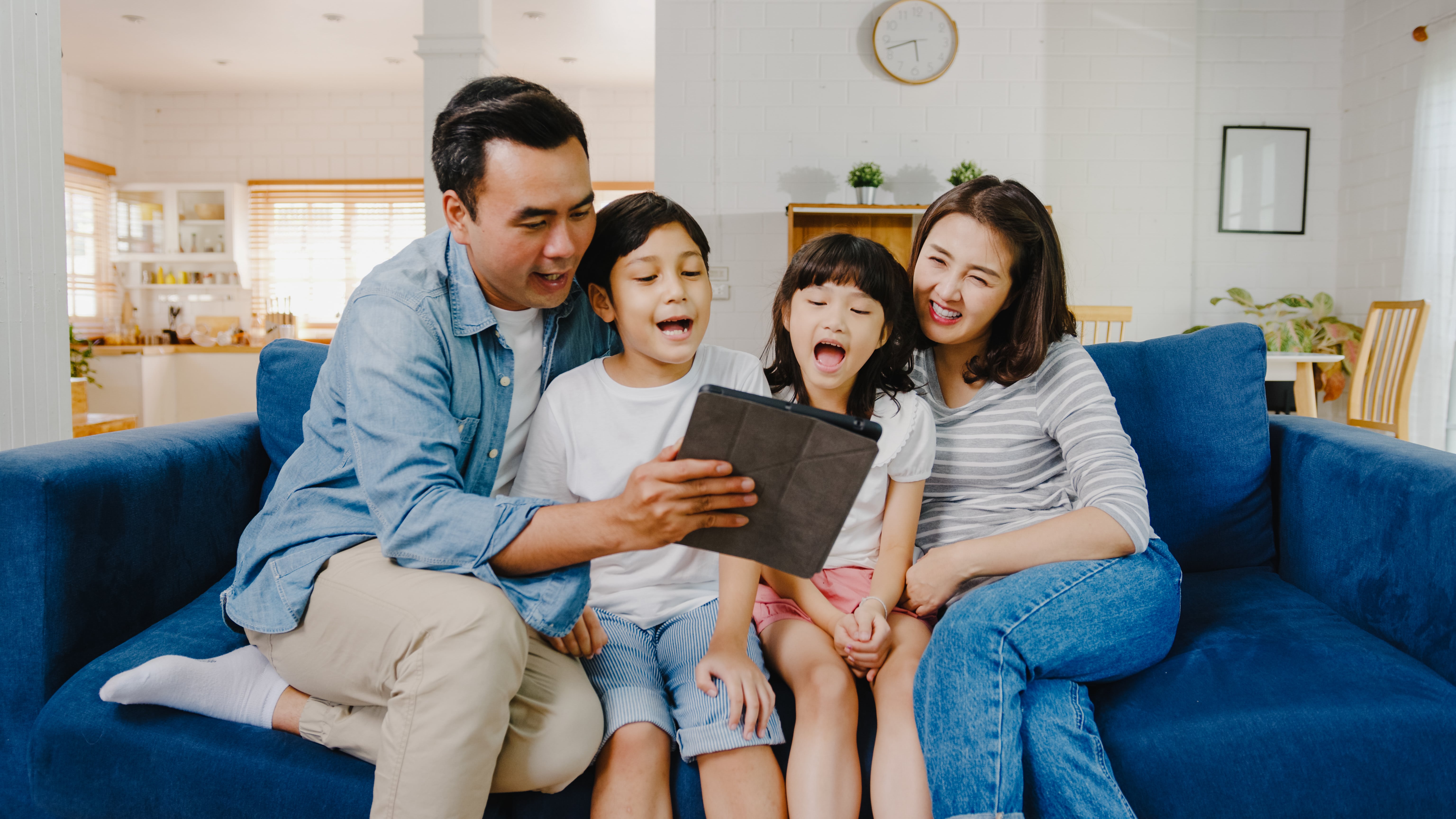 happy-cheerful-asian-family-dad-mom-kids-having-fun-using-digital-tablet-video-call-sofa-house-min