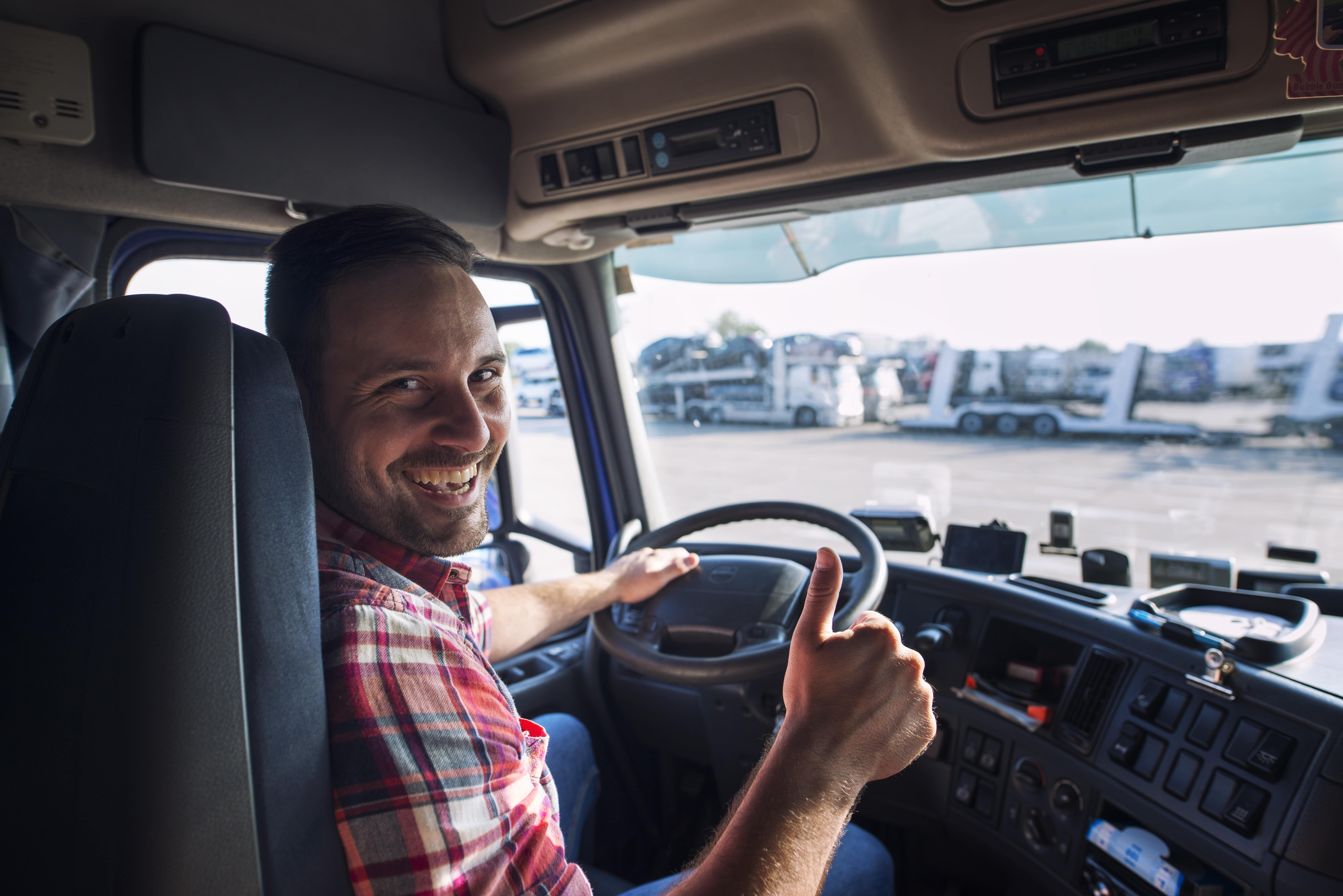 portrait-truck-driver-sitting-his-truck-holding-thumbs-up-min